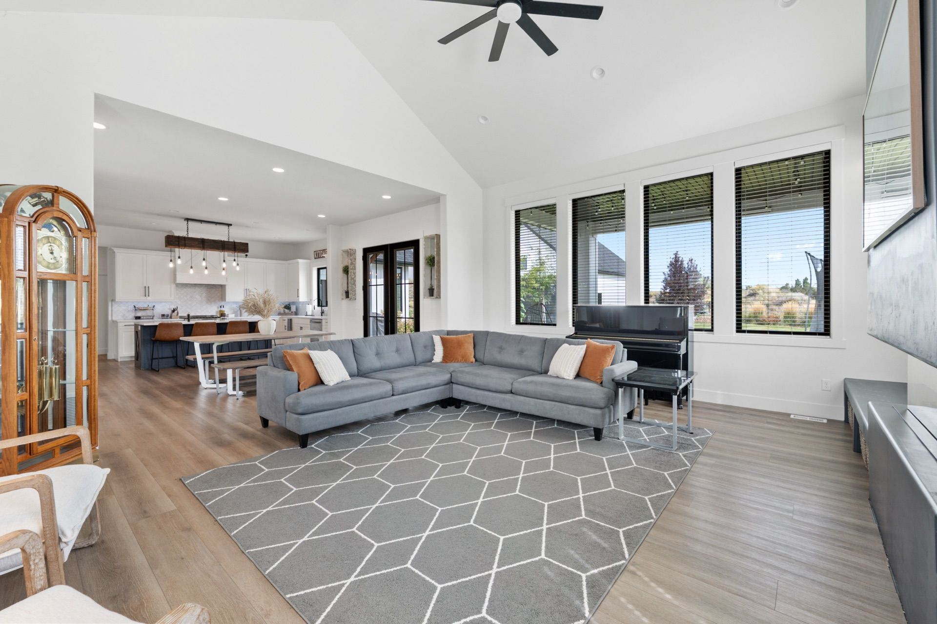 Open-plan great room with a grey sectional, vaulted ceiling and the kitchen and dining area beyond, the kind of layout a 3D tour explains